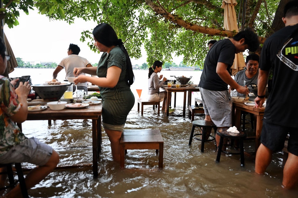 Diners stand while eating at the Chaopraya Antique Cafe as floodwaters from Thailand's Chao Phraya River...