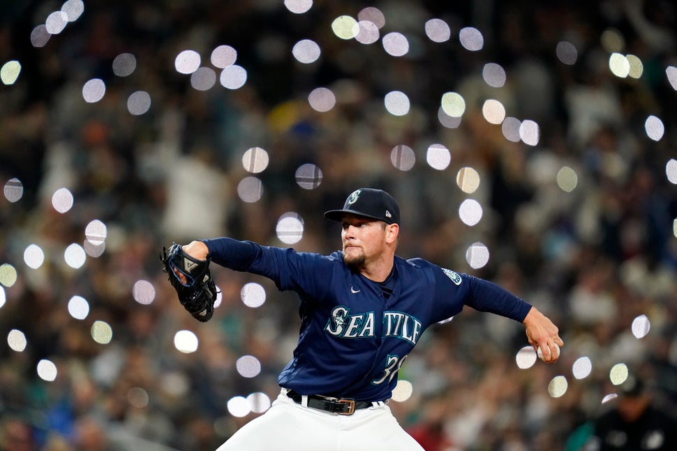 Cellphones light up in the seats behind Seattle Mariners reliever Anthony Misiewicz as he pitches against...