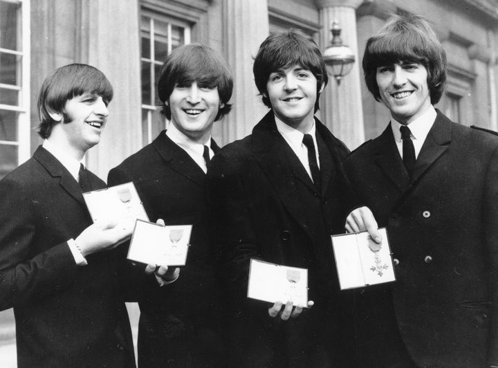 Los Beatles, de izquierda a derecha: Ringo Starr, John Lennon, Paul McCartney y George Harrison.  Se les ve mostrando las medallas del Miembro de la Orden del Imperio Británico que les entregó la Reina Isabel II en el Palacio de Buckingham en 1965.