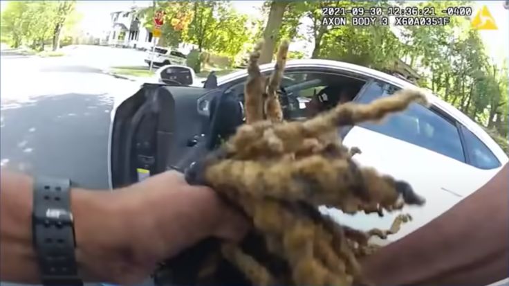 Police body camera footage shows an officer gripping Clifford Owensby's hair as the man is pulled out of his car and onto the ground during a traffic stop. 