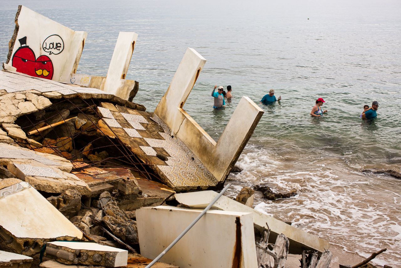 People swim by the ruins of a structure damaged during Hurricane María.