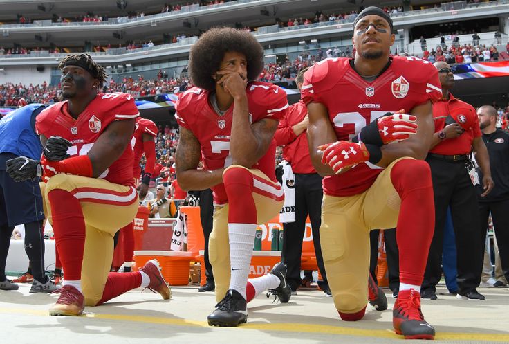 Eli Harold, Colin Kaepernick and Eric Reid of the San Francisco 49ers kneel on the sideline during the national anthem at a game in 2016.