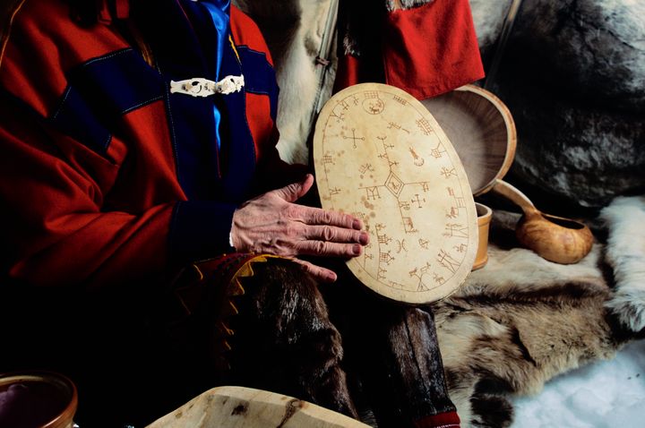 Η σαμάνος Esther Utsi κάθεται σε ένα Lavvu, την παραδοσιακή σκηνή Saami και κρατά ένα τύμπανο που παραδοσιακά χρησιμοποιείται για να επικοινωνήσει με τον κόσμο των πνευμάτων.
