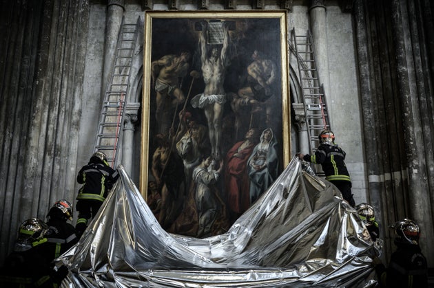 French firefighters protect a painting with a fireproof blanket during a fire drill aimed at preserving...