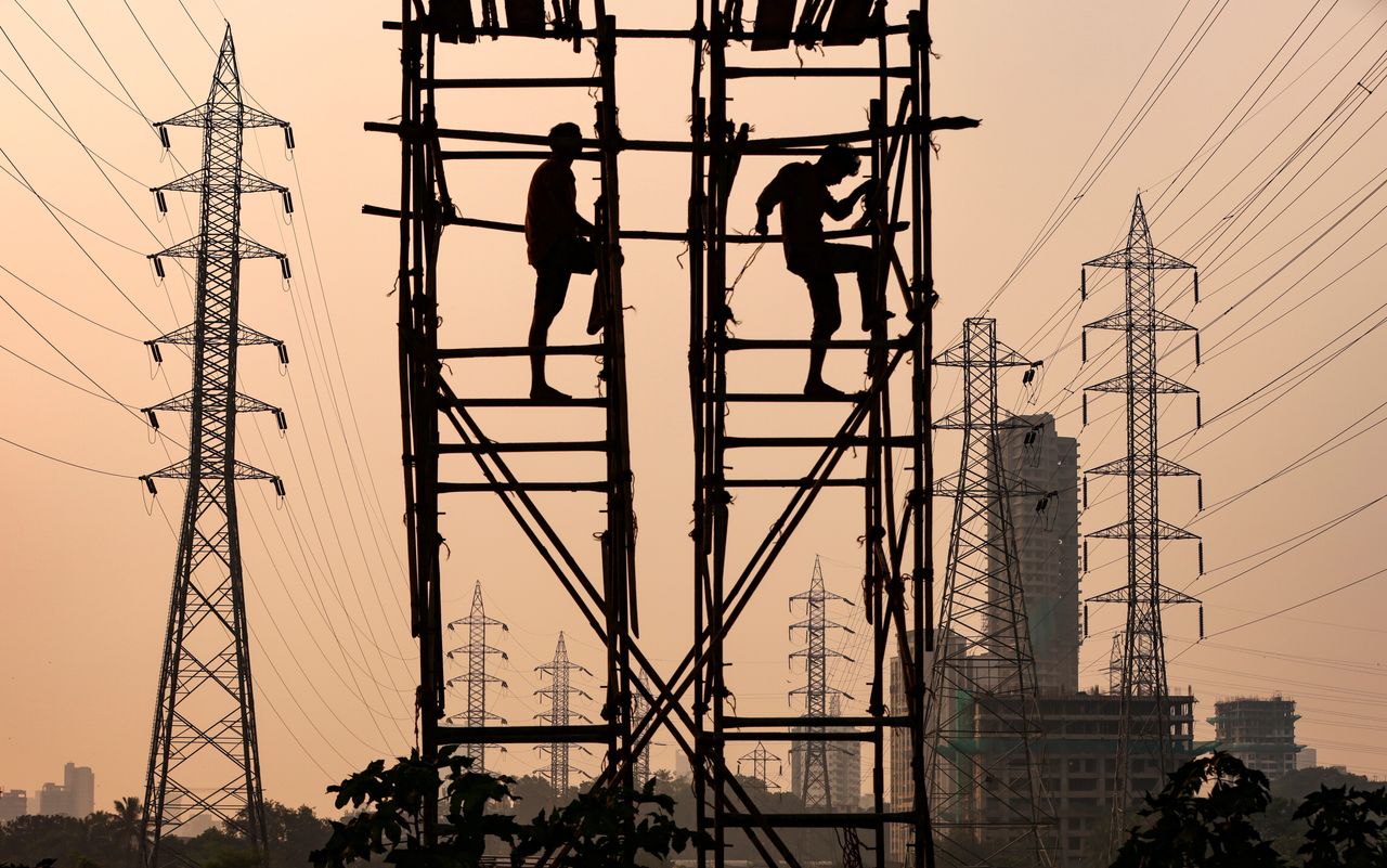 Laborers work next to electricity pylons in Mumbai, on Oct. 13.
