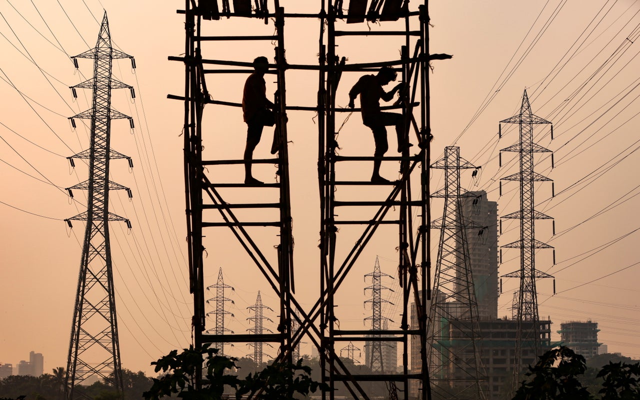 Laborers work next to electricity pylons in Mumbai, on Oct. 13.