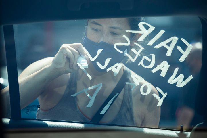 Donna Young, of IATSE Local 700 Motion Picture Editors Guild, writes a message in support of fair wages for all on a union member's car during a rally on Sept. 26 in Los Angeles.
