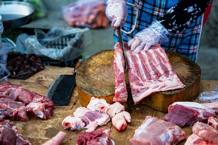 Traditional street market, people selling fresh meat on the sidewalk in Vietnam.