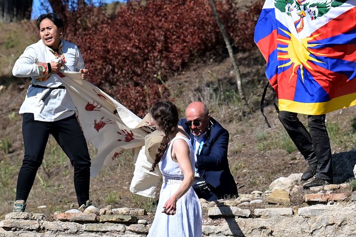 A security officer tries to stop protesters holding a banner and a Tibetan flag as they crash the flame lighting ceremony for the Beijing 2022 Winter Olympics. 