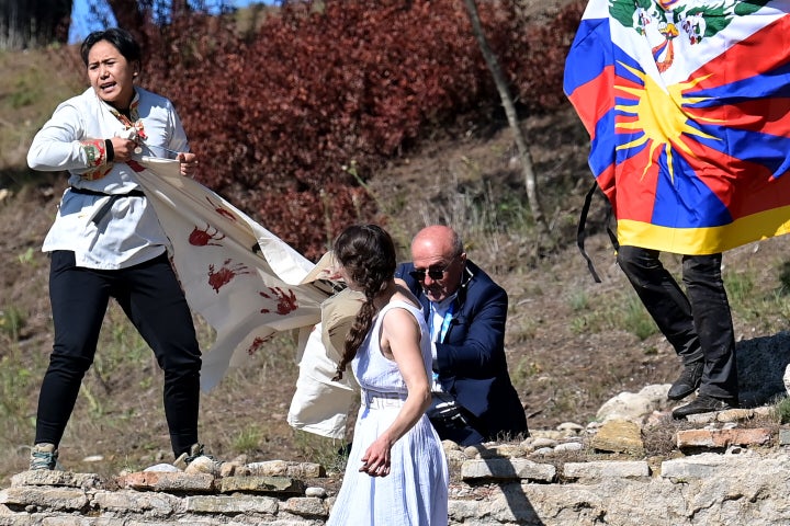 A security officer tries to stop protesters holding a banner and a Tibetan flag as they crash the flame lighting ceremony for the Beijing 2022 Winter Olympics. 