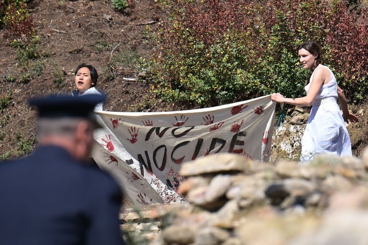 A police officer rushes to stop protesters holding a banner and the Tibetan flag (unseen) as they crash the start of the flame lighting ceremony for the Beijing 2022 Winter Olympics at the Ancient Olympia archeological site.