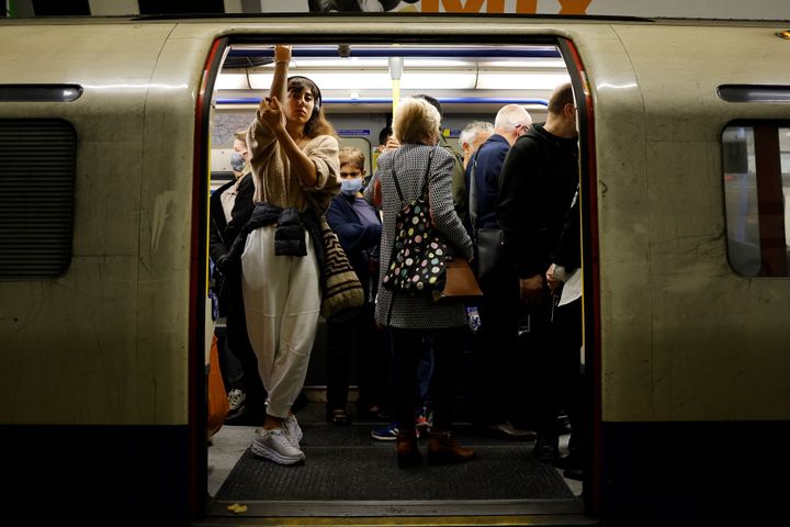 Commuters, some wearing face coverings to help prevent the spread of coronavirus, wait for the Tube.