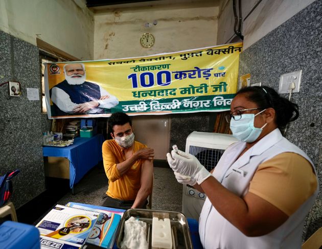 Ένας εργαζόμενος στον τομέα της υγείας εμβολιάζει έναν άνδρα δίπλα σε ένα πανό που ευχαριστεί τον πρωθυπουργό Ναρέντρα Μόντι για 1 δισεκατομμύριο δόσεις εμβολίου COVID-19 σε κυβερνητικό νοσοκομείο στο Νέο Δελχί, Ινδία, Πέμπτη, 21 Οκτωβρίου 2021. Η Ινδία χορήγησε 1 δισεκατομμύριο δόσεις COVID-19 -19 εμβόλιο, που αποτελεί ένα ορόσημο για τη χώρα της Νότιας Ασίας.