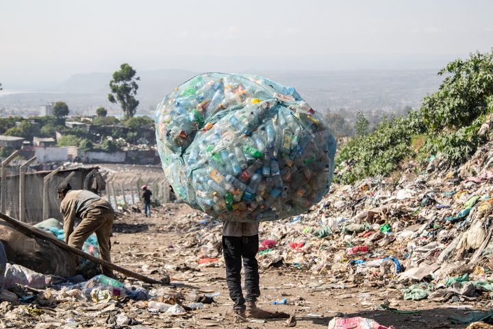 A man in Kenya carries a load of plastic garbage. 
