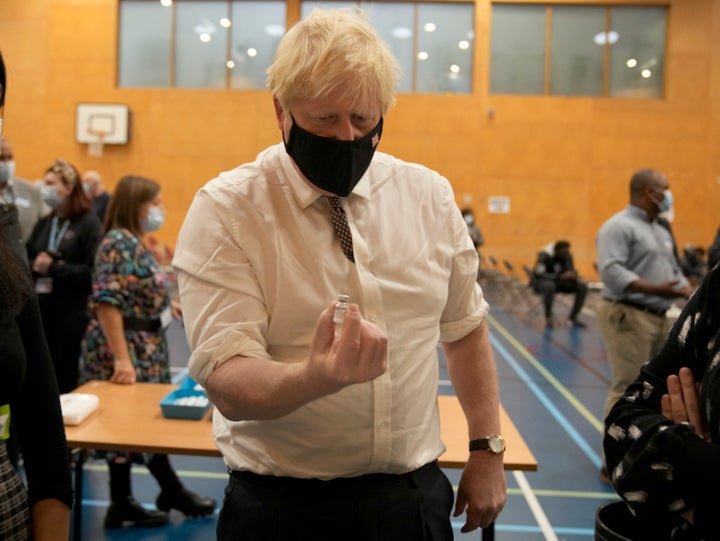 Prime minister Boris Johnson shakes a dose of the pfizer vaccine 