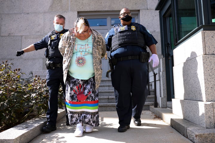 Police officers escort a protester out of the Department of Interior building after a sit-in held by climate activists on Oct. 14 in Washington, D.C.