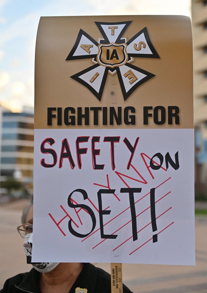 A tailor/seamstress holds a sign that reads "FIGHTING FOR SAFETY ON SET!" during a vigil held Saturday to honor cinematographer Halyna Hutchins.