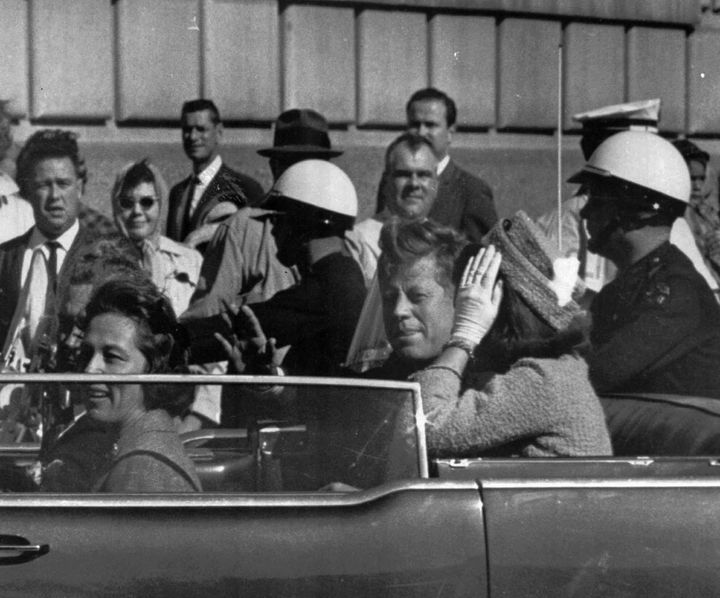 Ο πρόεδρος των ΗΠΑ με τη Τζάκι λίγο πριν πέσει νεκρός από πυροβολισμούς. 22 Νοεμβρίου 1963, Ντάλας. Στο αυτοκίντο βρίσκονται επίσης ο κυβερνής της Πολιτείας και η σύζυγο του. Το οπτικό υλικό με την αυτοκινητοπομπή του Κένεντι καθώς διέσχιζε αργά το Ντάλας σημάδεψε μια ολόκληρη γενιά και παραμένει πηγή θεωριών συνωμοσίας.  (AP Photo, File)