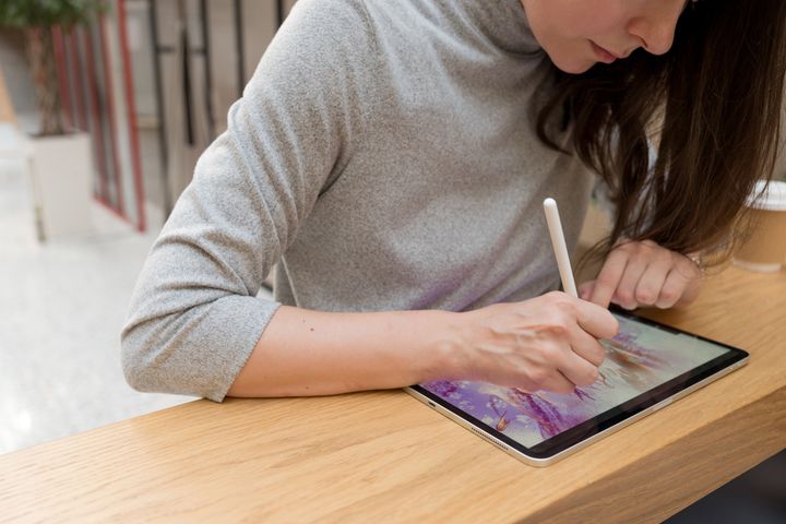 A digital artist draws on a graphic screen tablet using a stylus