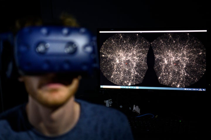 In this Oct. 12, 2021, file photo, Hadrien Gurnel, software engineer at EPFL's Laboratory for Experimental Museology, explores with a virtual reality helmet the most detailed 3D map of the universe with the virtual reality software VIRUP.