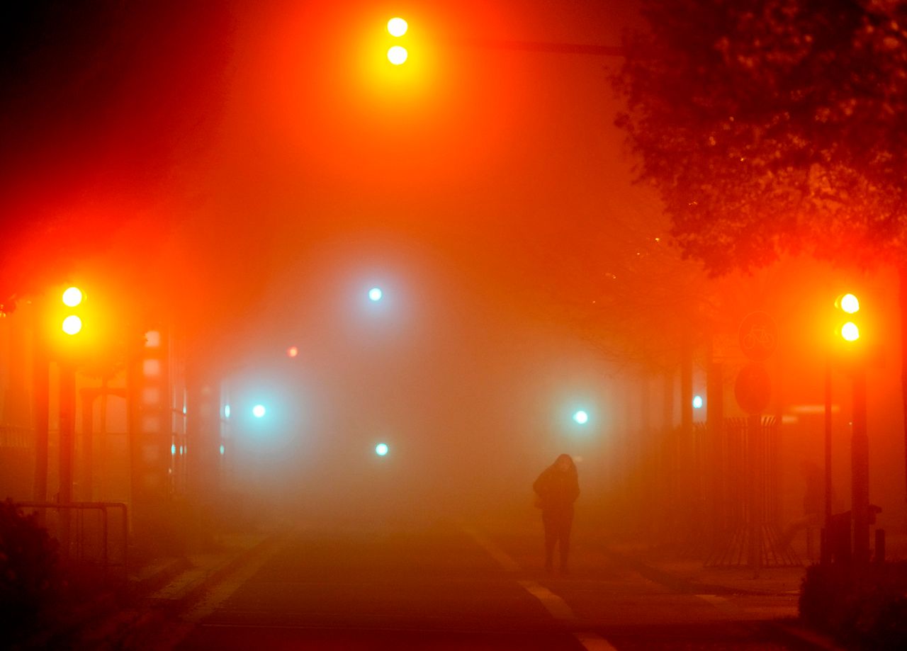 A woman crosses the street on a foggy morning in Frankfurt, Germany, on Friday.