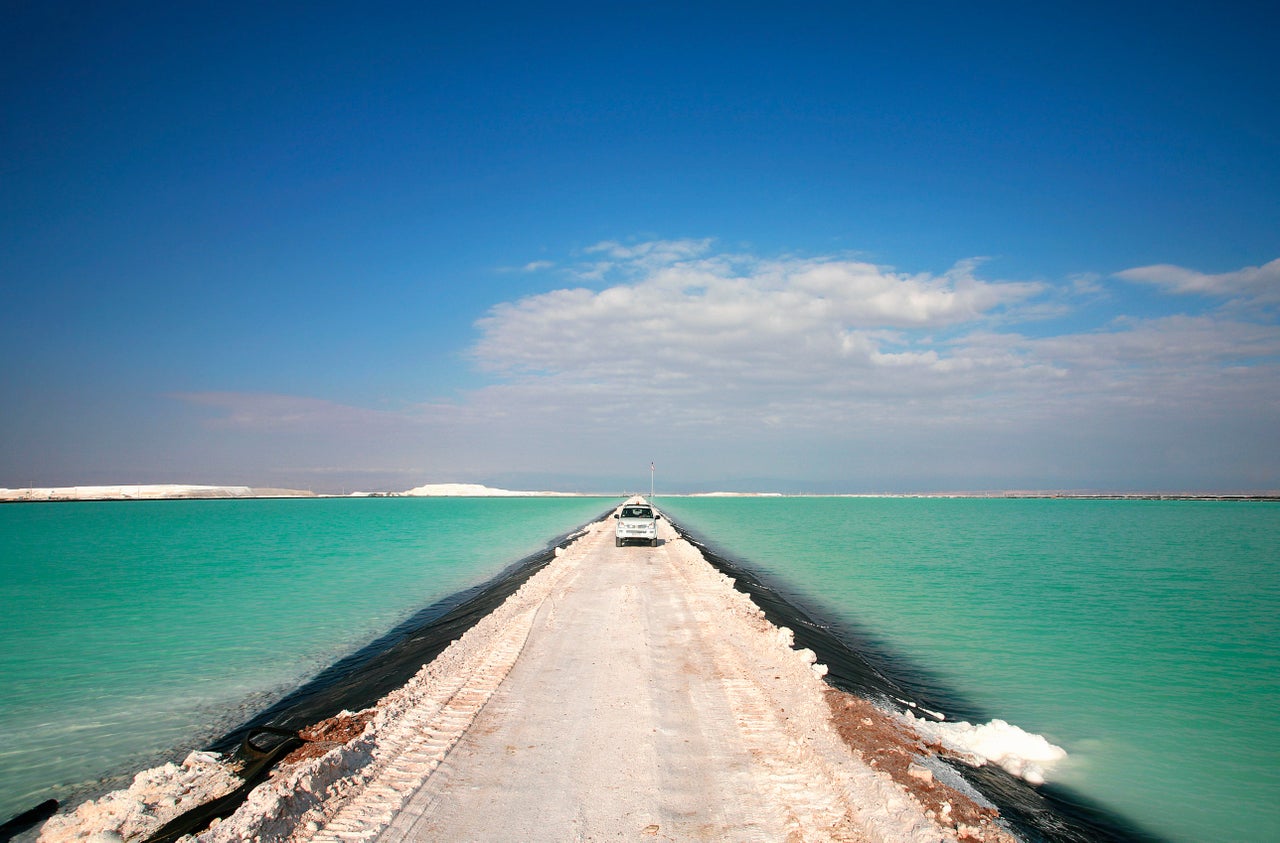 A pick-up drives through the brines pools of the Salar de Atacama, where lithium is extracted as the sun evaporates water.