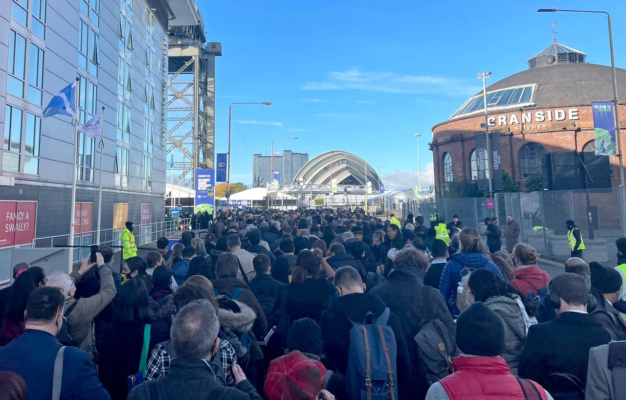 Cop26 delegates wait in a long queue for entrance to the summit at the Scottish Exhibition Centre in Glasgow