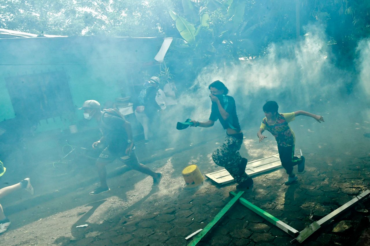 People run away from tear gas shot by riot police as authorities try to implement an eviction order to evacuate families living in alleged illegal constructions, in Medellin, Colombia, on Nov. 3. The Moravia neighborhood is known for having been built on a garbage dump and for being from where late drug lord Pablo Escobar set up his first political campaign.