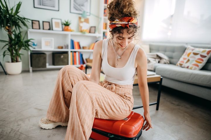 Young woman preparing for road trip, packing suitcase