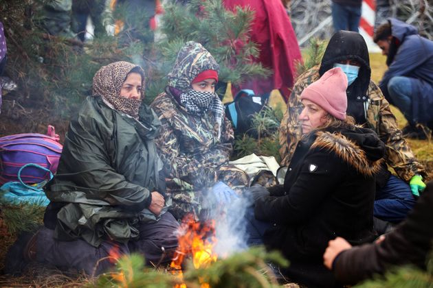 ベラルーシとポーランドの国境で、たき火のそばに座る移民たち