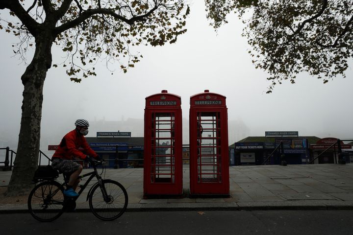 Ένας ποδηλάτης που φοράει μάσκα περνάει από κόκκινους τηλεφωνικούς θαλάμους στο Λονδίνο