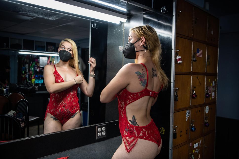 Stripper Bella, a 29-year-old cancer survivor and mother of two, looks into the mirror in the changing rooms of Mons Venus. 