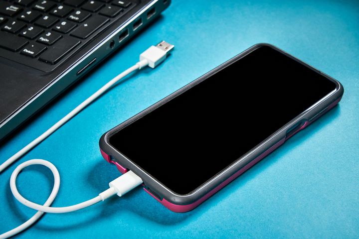 Close up image of smartphone charging using laptop