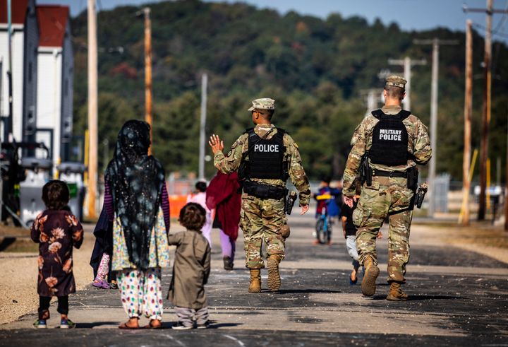 Military police walk past Afghan refugees at the Ft. McCoy Army base in Wisconsin in September.
