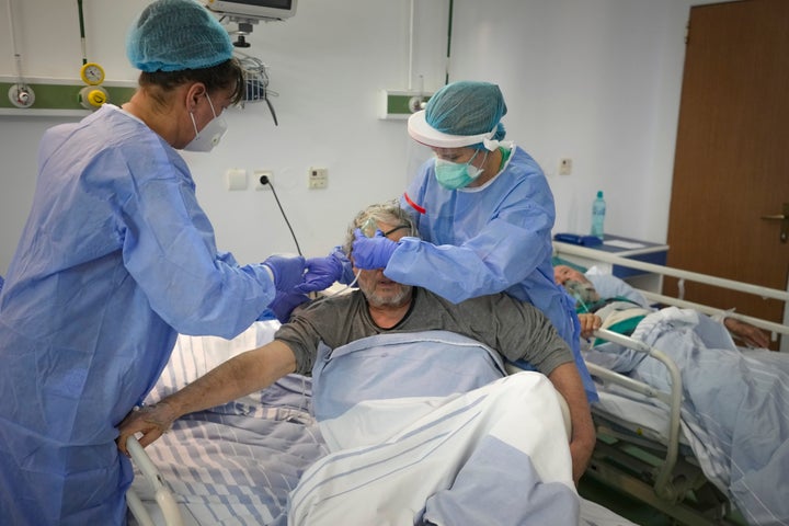 FILE - Doctor Petruta Filip, right, and a colleague place an oxygen mask on a man in the COVID-19 section at the University Emergency Hospital in Bucharest, Romania, Friday, Oct. 22, 2021. In much of Eastern Europe, coronavirus deaths are high and vaccination rates are low, but politicians have hesitated to impose the measures curb the virus that experts are calling for. A World Health Organization official declared earlier this month that Europe is again the epicenter of the coronavirus pandemic. (AP Photo/Vadim Ghirda, File)