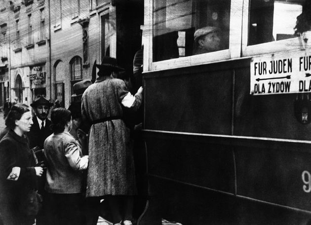 1941年2月1日、ポーランドのクラクフに設けられたユダヤ人の強制居住区での写真。「ダビデの星の腕章」をつけたユダヤ人が路面電車に乗っている。車両の壁にはユダヤ人が車両後部に座るように注意書きが書かれている。
