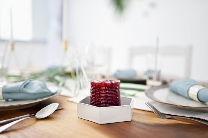 Cranberry sauce, still in the shape of a can, served on a beautiful set Christmas table.
