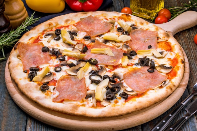 Capricciosa pizza with artichokes on wooden table.