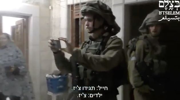 Un soldado israelí toma fotos a niños palestinos, mientras les pide que digan