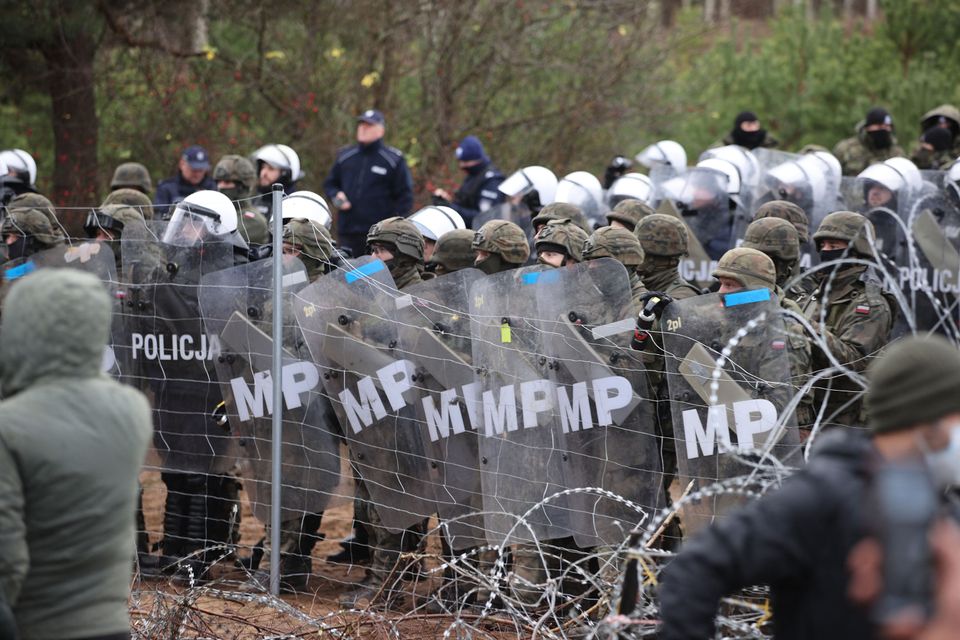 TOPSHOT - A picture taken on November 8, 2021 shows Poland's law enforcement officers watching migrants...