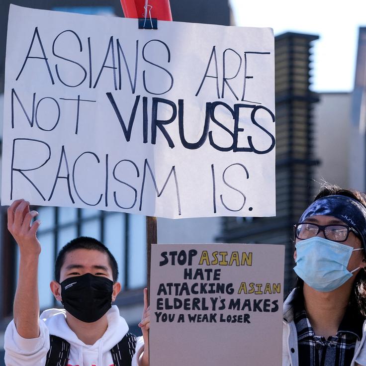 A demonstrator holds a sign that reads "Asians are not viruses, racism is," at a demonstration at the Japanese American National Museum in Little Tokyo in Los Angeles on March 13.