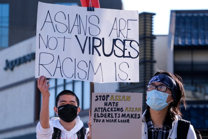 A demonstrator holds a sign that reads "Asians are not viruses, racism is," at a demonstration at the Japanese American National Museum in Little Tokyo in Los Angeles on March 13.