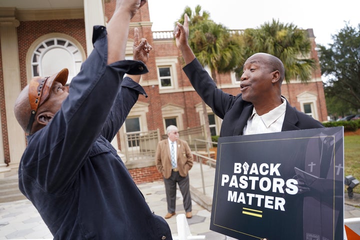 Rev. Siegfried Darcell White, at right, points the sky at the Glynn County courthouse before a court session in the trial of the killers of Ahmaud Arbery on Nov. 18 in Brunswick, Georgia.