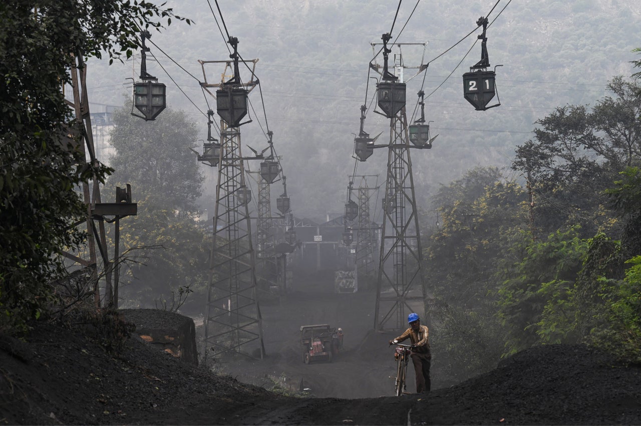 A worker pushes his bicycle under a line of cable trolleys transporting coal in Sonbhadra, Uttar Pradesh, India, on Nov. 19.