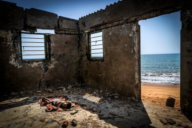 西アフリカのトーゴ共和国で撮影され、海岸侵食により破壊された自宅で寝ている少年が写っている。