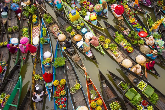 Ντόπιοι συγκεντρώνονται για να αγοράσουν και να πουλήσουν φρέσκα φρούτα, λαχανικά και μπαχαρικά σε πλωτή αγορά.