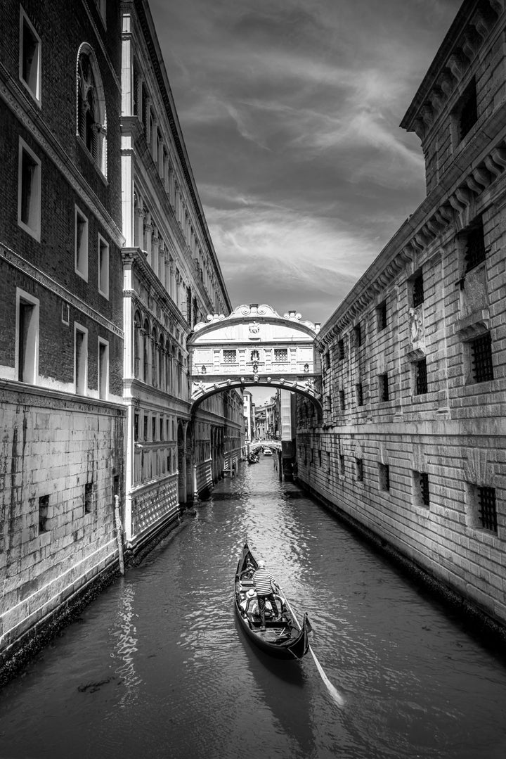 A gondola makes it way down the river in Venice taking tourists on the scenic route, photographed by David Chofardet.