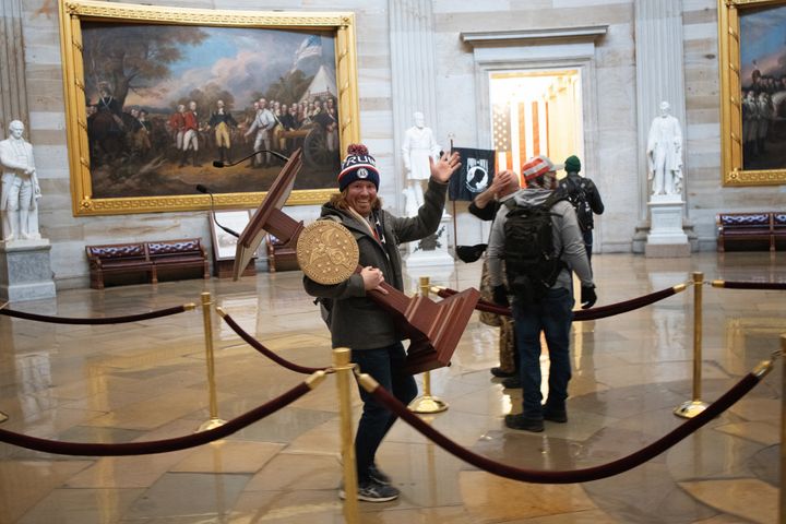 A Donald Trump supporter, later identified as Adam Johnson from Florida, smiles and waves as he carries Speaker Nancy Pelosi's rostrum inside the U.S. capital during the January 6 riots.