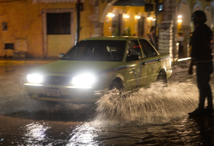 Un coche atraviesa una calle inundada