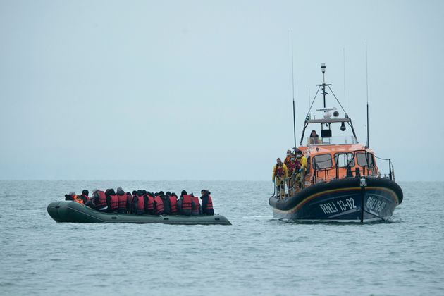 Migrants are helped by RNLI (Royal National Lifeboat Institution) lifeboat before being taken to a beach...